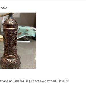 May include: An antique-style pepper grinder with a copper finish. The grinder features intricate embossed patterns and a crank handle. The design is reminiscent of vintage kitchen tools. The pepper grinder is a kitchen utensil.