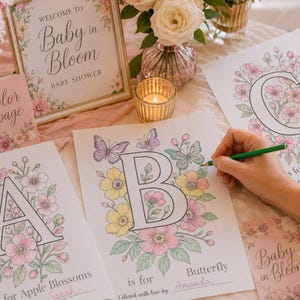 Baby in Bloom baby shower activity with guests coloring floral alphabet pages for Baby’s First ABC Book keepsake. Printable baby shower game featuring blush pink flowers, butterfly coloring pages, and personalized ABC book pages guests color and sign for baby. Elegant floral baby shower decor and interactive keepsake activity for a girl baby shower.