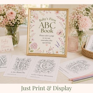 Baby in Bloom baby shower table setup featuring Baby’s First ABC Book sign with floral alphabet coloring pages for guests to color during the shower. Elegant blush pink floral baby shower activity with printable ABC keepsake book, coloring pages A–Z, and baby shower table decor. Printable baby shower game and interactive guest activity for creating a personalized keepsake for baby.