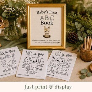 Woodland baby shower ABC book printable displayed in a cozy forest-themed baby shower setup with woodland animal coloring pages, gold framed ABC book sign, rustic decor, colored pencils, and gender neutral baby shower activity. Printable baby shower keepsake game featuring woodland animals including bear, chipmunk, and acorn coloring sheets for guests to color and create a personalized baby keepsake book.