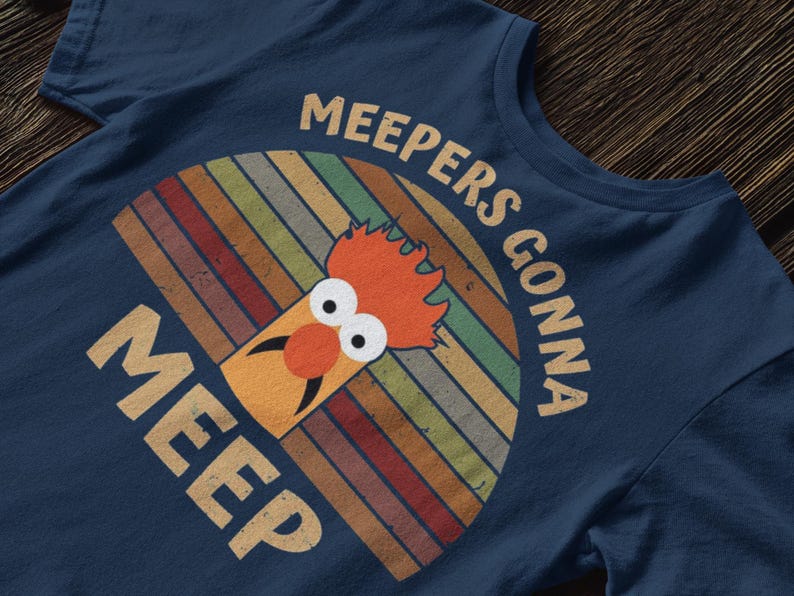 Peut inclure: T-shirt bleu marine avec un motif r&eacute;tro d'un personnage de Muppet et le texte "MEEPERS GONNA MEEP". Le motif comprend un arc-en-ciel color&eacute;.