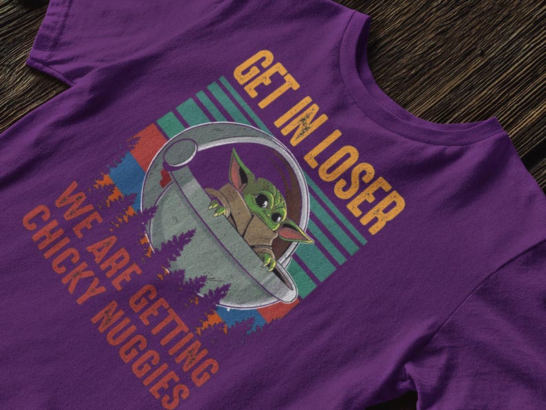 K&ouml;nnte beinhalten: Lilafarbenes T-Shirt mit einer Grafik eines Charakters in einer Kapsel und dem Text "GET IN LOSER WE ARE GETTING CHICKY NUGGIES" in Orange und Wei&szlig;. Das Design enth&auml;lt einen gr&uuml;n, blau und rot gestreiften Hintergrund.