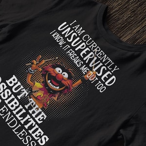 Puede incluir: Camiseta negra con una imagen de dibujos animados de Animal de The Muppets. El texto dice: "I AM CURRENTLY UNSUPERVISED, I KNOW, IT FREAKS ME OUT TOO, BUT THE POSSIBILITIES ARE ENDLESS."