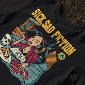 Peut inclure: T-shirt noir avec une illustration de dessin animé et le texte "SICK, SAD FICTION" en jaune. Le dessin montre une personne avec un crâne, une pizza et des livres. Une pièce de 10 centimes est également visible.