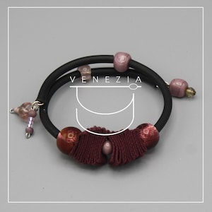 May include: A black bracelet with a burgundy tassel and decorative beads in shades of pink and purple. The word "VENEZIA" is printed on the image.