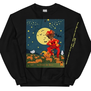 May include: Black sweatshirt featuring a Halloween-themed graphic. The graphic depicts a cat in a jester costume standing in a pumpkin patch under a full moon. The text "La foot de Boo" is at the bottom.