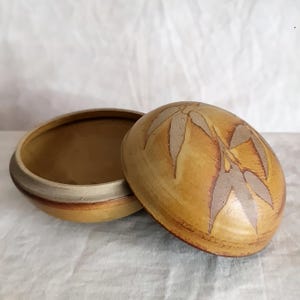 May include: A set of three ceramic mugs with a speckled, matte finish in cream, light grey, and dark grey. Each mug has a simple, minimalist design and a rounded handle.