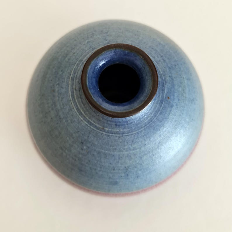 Pu&ograve; includere: Un vaso di ceramica blu con corpo rotondo e collo stretto. Il vaso ha un bordo marrone scuro e un interno blu. Il fondo del vaso ha una tonalit&agrave; rosso-rosata. Il vaso &egrave; probabilmente fatto a mano e ha una superficie strutturata.