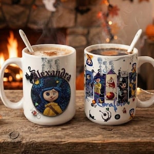 May include: Two white ceramic mugs with handles and white spoons. The left mug features a circular illustration of a character with blue hair and the name Alexandra. The right mug displays a vertical collage of characters and the text Coraline.