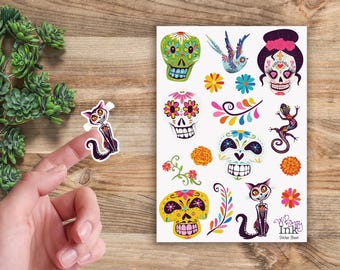 May include: A sticker sheet featuring colorful Day of the Dead themed illustrations including sugar skulls, a cat, a lizard, a bird, and floral accents. The sheet includes the text Whimsy Ink Sticker Sheet in the bottom right corner.