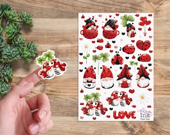 Pode incluir: Uma folha de autocolantes com gnomos com tema de joaninhas vermelhas e pretas, corações, trevos e margaridas. A folha inclui o texto LOVE e Whimsy Ink Sticker Sheet. Um autocolante de gnomo com um trevo é mostrado separadamente.
