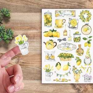 May include: A sticker sheet featuring various watercolor illustrations of lemons, yellow flowers, a teapot, a gnome, and kitchen items, with text including Lemon, Farmers Market Fresh Lemons, and Whimsy Ink Sticker Sheet.