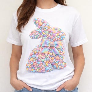 Op de afbeelding: Wit T-shirt met een kleurrijk konijnontwerp gemaakt van pastelkleurige stenen en een bijpassende strik. De konijnengrafiek is gecentreerd op het shirt, wat zorgt voor een grillige en feestelijke uitstraling. Het shirt heeft een klassieke ronde hals.