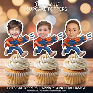 May include: Three cupcakes topped with white frosting, each adorned with a personalized image of a child holding a toy gun. The image is approximately 3 inches tall. Text on the image reads: "Personalized CUPCAKE TOPPERS" and "PHYSICAL TOPPERS | APPROX. 3 INCH TALL IMAGE".