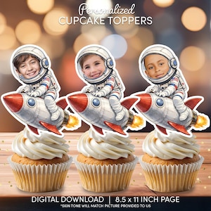 Op de afbeelding: Drie cupcakes met witte glazuur, elk bekroond met een gepersonaliseerde afbeelding met astronautenthema die op een raket rijdt. De afbeelding bevat de tekst "Personalized CUPCAKE TOPPERS" en "DIGITALE DOWNLOAD | 21,6 x 27,9 CM PAGINA".