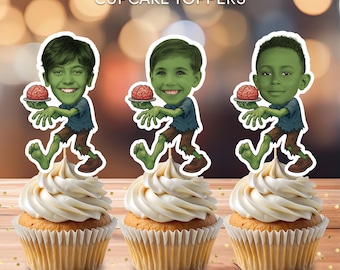 May include: Three cupcakes topped with personalized zombie-themed cupcake toppers. Each topper features a cartoon image of a person holding a brain. The cupcakes have white frosting and are on a wooden surface. Text on the image reads "Personalized CUPCAKE TOPPERS".