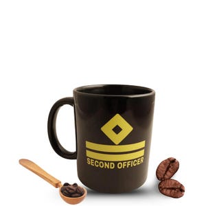 Può includere: Tazza in ceramica nera con un design a rombi e due strisce gialle e le parole "SECOND OFFICER". Un cucchiaio di legno pieno di chicchi di caffè e due chicchi di caffè sono accanto alla tazza.