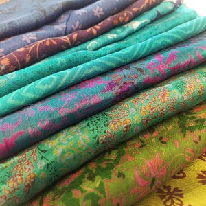 Puede incluir: Una pila de retazos de tela coloridos con patrones florales en tonos verdes, azules y rosas.