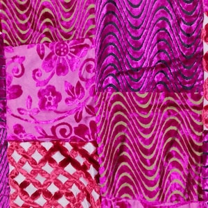 May include: A patchwork of vibrant fuchsia velvet fabric squares. The squares feature various patterns, including floral designs, wavy lines, and diamond lattice. The textures and colors create a rich, luxurious aesthetic.