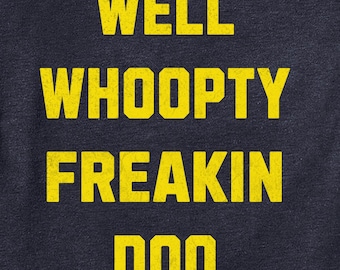 May include: A navy blue t-shirt with the text "WELL WHOOPTY FREAKIN DOO" printed in yellow.