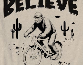 May include: Black and white illustration of a monkey riding a bicycle in a desert landscape with the word "BELIEVE" at the top of the image.
