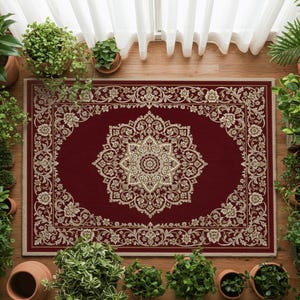 Puede incluir: Una alfombra rectangular con un fondo rojo intenso que presenta un gran medallón floral central intrincado y un borde ornamentado a juego en tonos crema y beige. El diseño incluye enredaderas simétricas y motivos florales detallados.
