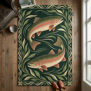 Puede incluir: Una alfombra rectangular con fondo verde oscuro y dos truchas nadando en círculo. Los peces tienen cuerpos moteados con franjas laterales rosadas. La alfombra está enmarcada por un borde de hojas verdes estilizadas.