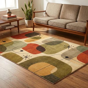 May include: A rectangular area rug with a mid-century modern design. The rug features a cream background with large, colorful, abstract shapes in shades of orange, green, brown, and gray. Black lines and starburst details add to the design.