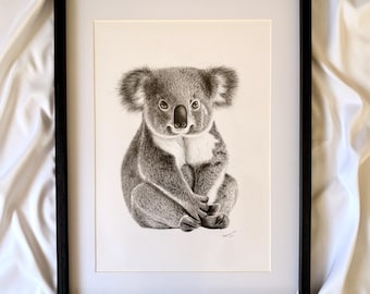 May include: A framed black and white pencil drawing of a koala bear. The koala is depicted sitting with its paws crossed, showcasing detailed fur and facial features. The artwork is set against a white background within a black frame.