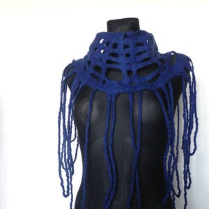 May include: A dark blue felted wool neck piece with a unique design. The top portion features a series of cut-out shapes, while long, dangling strands hang down. The neck piece is displayed on a black mannequin against a white background.