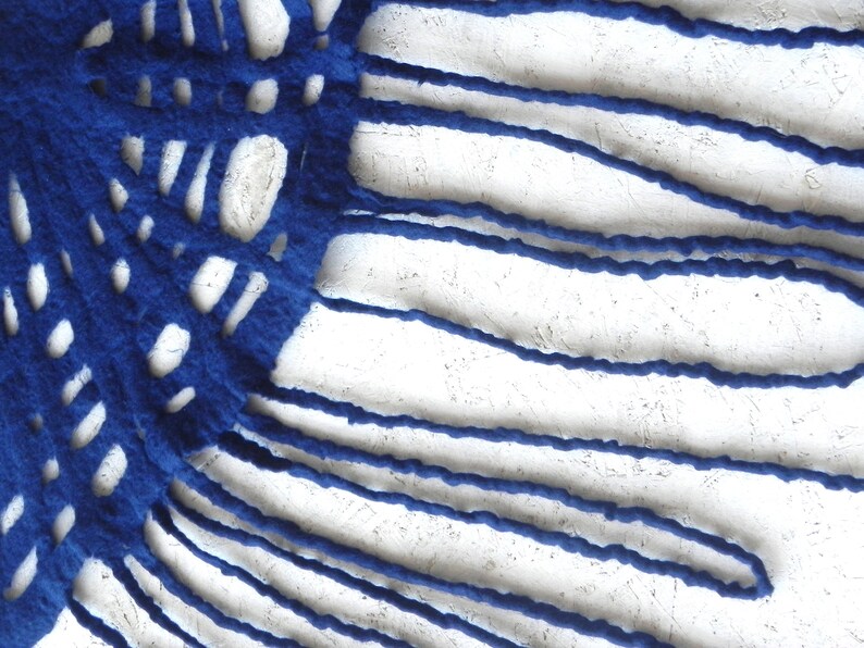 May include: Abstract textile art piece featuring a vibrant blue, textured fabric with a cut-out design. The blue fabric is set against a white, textured background, creating a striking contrast. The design includes both linear and circular cut-outs.