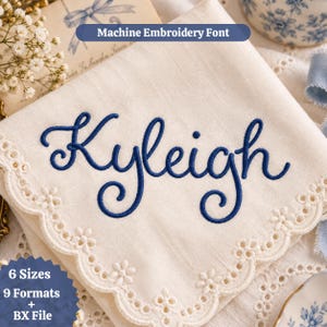Peut inclure: Une serviette en tissu couleur crème avec un bord festonné brodé d'œillets. Le prénom Kyleigh est cousu au centre avec un fil bleu foncé en écriture cursive. Le texte en haut indique Machine Embroidery Font et en bas 6 Sizes 9 Formats + BX File.