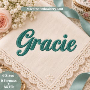 Puede incluir: Un pañuelo de tela de color blanco roto con un borde de encaje festoneado, que presenta el nombre Gracie bordado en hilo verde azulado oscuro. El texto Machine Embroidery Font, 6 Sizes, 9 Formats + BX File es visible.