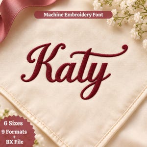 May include: A cream-colored fabric featuring the name Katy embroidered in a dark red script font. The text Machine Embroidery Font is displayed at the top, while a maroon badge at the bottom reads 6 Sizes, 9 Formats + BX File.