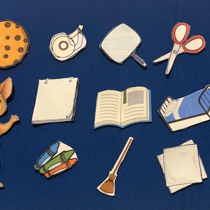 May include: A brown and white mouse wearing blue overalls stands next to a variety of school supplies, including a book, scissors, crayons, a glass of milk, a straw, a cookie, and a notepad.