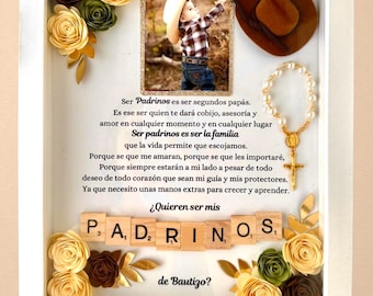 May include: A white frame with a photo of a young boy wearing a cowboy hat. The frame is decorated with paper flowers, a rosary, and a cowboy hat. The text in the frame reads "Ser Padrinos es ser segundos papás. Es ese ser quien te dará cobijo, asesoría y amor en cualquier momento y en cualquier lugar Ser padrinos es ser la familia que la vida permite que escojamos. Porque se que me amaran, porque se que les importaré, Porque siempre estarán a mi lado a pesar de todo deseo de todo corazón que sean mi guía y mis protectores. Ya que necesito unas manos extras para crecer y aprender. ¿Quieren ser mis P. A, D, RINO, S, de Bautizo?"