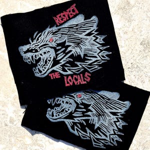 May include: Two black fabric patches featuring a grey wolf head with red eyes and snarling teeth. The text "RESPECT THE LOCALS" is in red above and below the wolf head design.