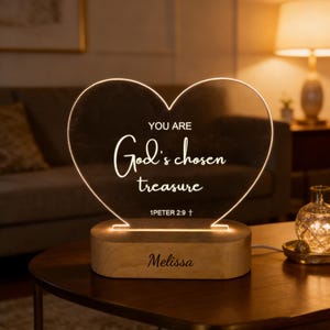 May include: A heart-shaped LED night light with the words "YOU ARE God's chosen treasure" and "1 PETER 2:9" etched on the clear acrylic. The light sits on a wooden base with the name "Melissa" engraved. The light emits a warm glow.