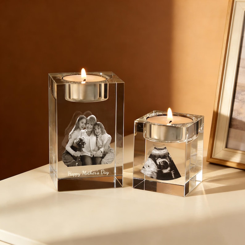 May include: Two clear glass candle holders with lit candles. One features a family photo, the other an ultrasound image. The text "Happy Mother's Day" is visible on the larger holder. A warm, sentimental gift.