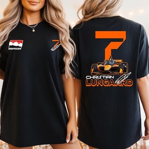 May include: Black t-shirt featuring the INDYCAR logo and a stylized racing car design with the number 7 and the name CHRISTIAN LUNGAARD in orange and white. The shirt has a crew neck and short sleeves.