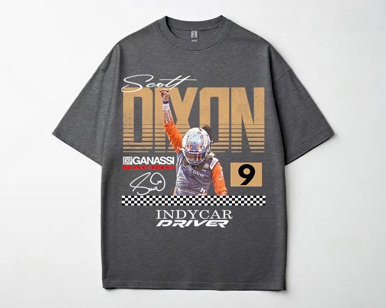 May include: Dark gray t-shirt featuring a graphic of IndyCar driver Scott Dixon. The design includes the name "Scott Dixon" in a stylized font, the number "9", and the words "INDYCAR DRIVER". The shirt has a crew neck and short sleeves.