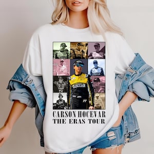May include: White t-shirt featuring a collage of images of a race car driver. The design includes a central portrait of the driver in a black and yellow racing suit, surrounded by smaller images. Text at the bottom reads "CARSON HOCEVAR THE ERAS TOUR."