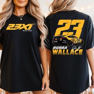 Könnte beinhalten: Schwarzes T-Shirt mit gelbem und schwarzem Rennsport-Design. Auf der Vorderseite steht "23XI Racing" in Gelb. Auf der Rückseite befindet sich eine Rennwagen-Grafik, die Nummer "23" und der Name "Bubba Wallace".