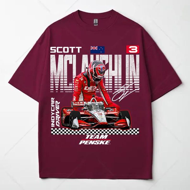 May include: Burgundy t-shirt featuring a graphic of an IndyCar driver in a red racing suit and helmet, with a race car. The shirt includes the driver's name, number 3, and the words "Team Penske."