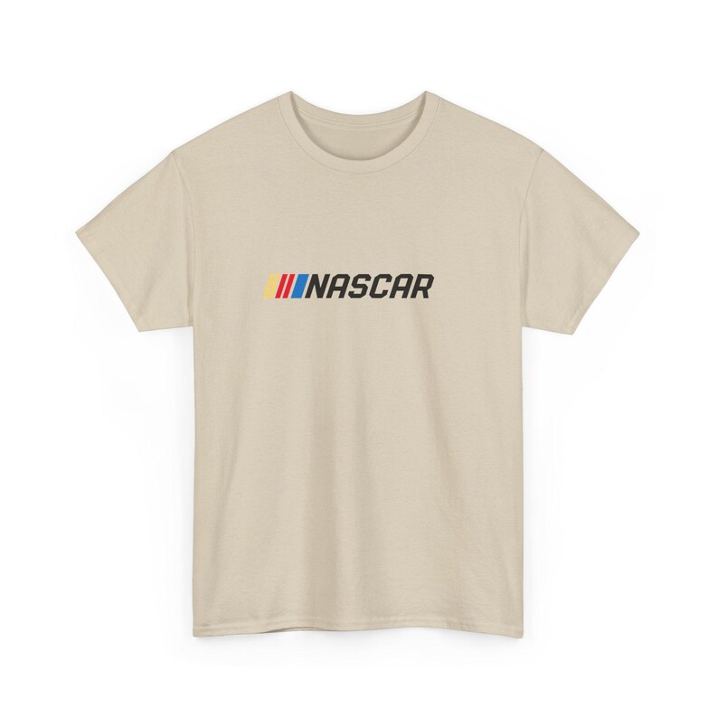 May include: A beige t-shirt featuring the word "NASCAR" in black, with a colorful stripe design above the text. The shirt is a short-sleeved crew neck style.