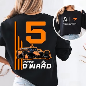 May include: Black sweatshirt featuring a large orange number 5 and a race car graphic. The text "PATO O'WARD" is below the car. The right sleeve shows the Arrow McLaren Indycar Team logo.