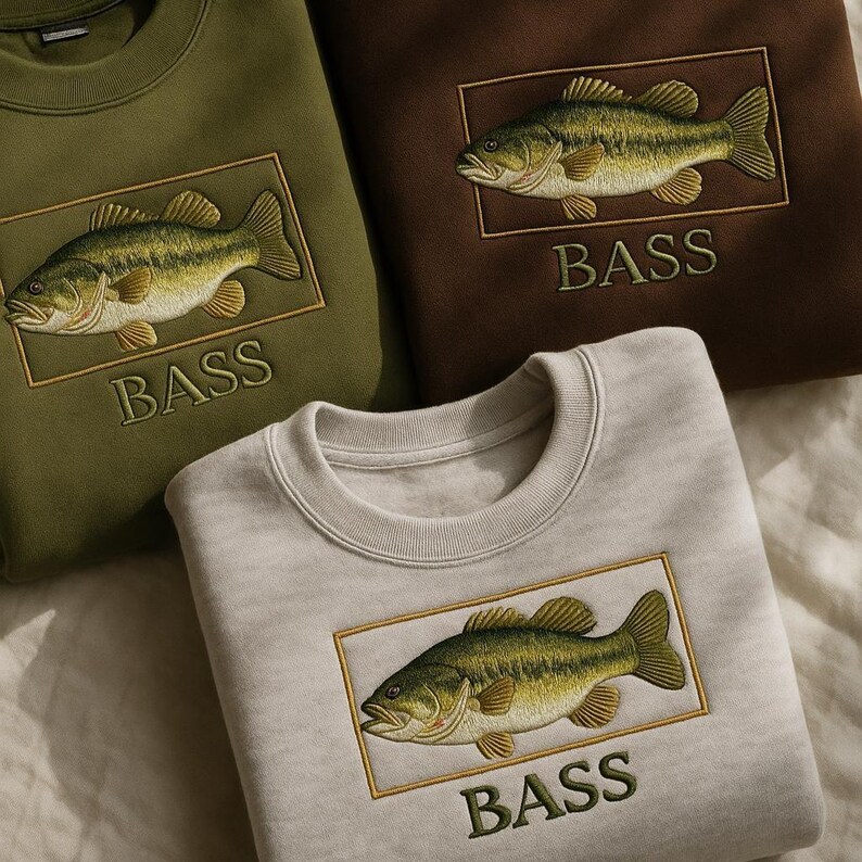 May include: Crewneck sweatshirts in olive green, brown, and light gray, each embroidered with a detailed largemouth bass design within a gold rectangular frame. The word "BASS" is embroidered below the fish in a matching green thread.