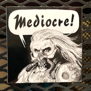 May include: Square sticker featuring a black and white illustration of a character with a mask and long hair. A speech bubble above the character reads "Mediocre!" in bold, black text. The sticker has a glossy finish.