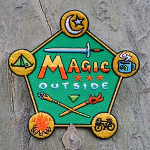 May include: A green, star-shaped patch with the words "MAGIC OUTSIDE" in orange and yellow letters. The patch has various embroidered images including a tent, a sword, a campfire, a mug of coffee, a crescent moon, and a bicycle.