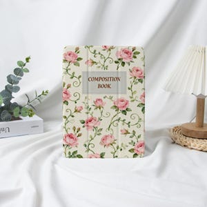 Puede incluir: Una funda para tableta con diseño floral. Tiene un fondo crema con rosas rosas y vides verdes. La etiqueta rectangular en el centro dice "COMPOSITION BOOK".